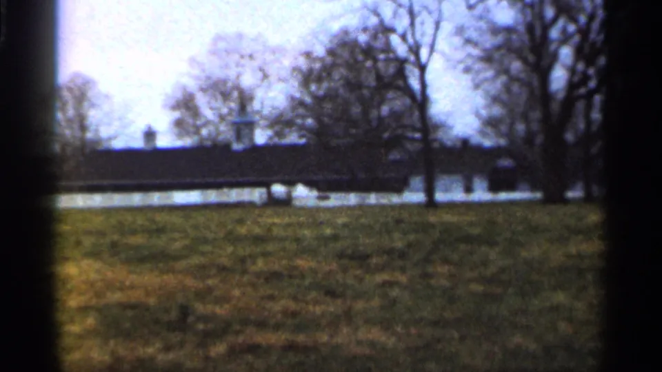 1966 Georgia rural scene showing a long dark building behind white fencing, with bare trees and open grass.