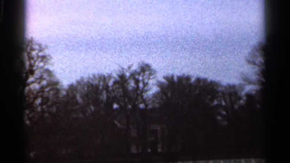 1966 Georgia 8mm frame showing bare trees, pale sky, and a small light-colored building partly obscured near the lower frame.