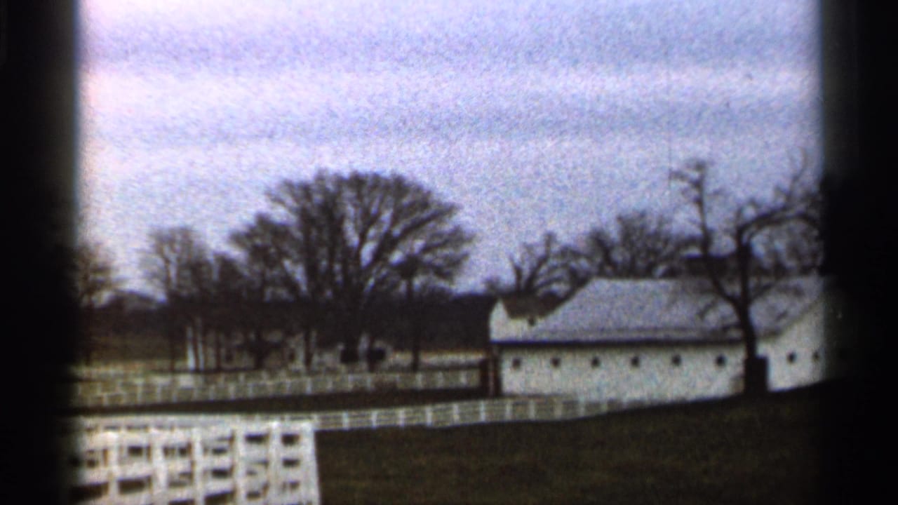 1966 Georgia 8mm frame showing a white farmhouse or outbuilding behind fences, with leafless trees and a grassy field.