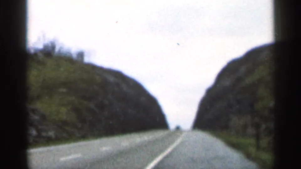 1966 Georgia road view from an 8mm home movie, with the car no longer visible and hills rising on both sides.