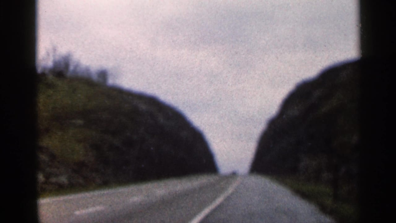 1966 Georgia 8mm road-trip view of a two-lane road passing between rocky, wooded hills under a washed-out sky.