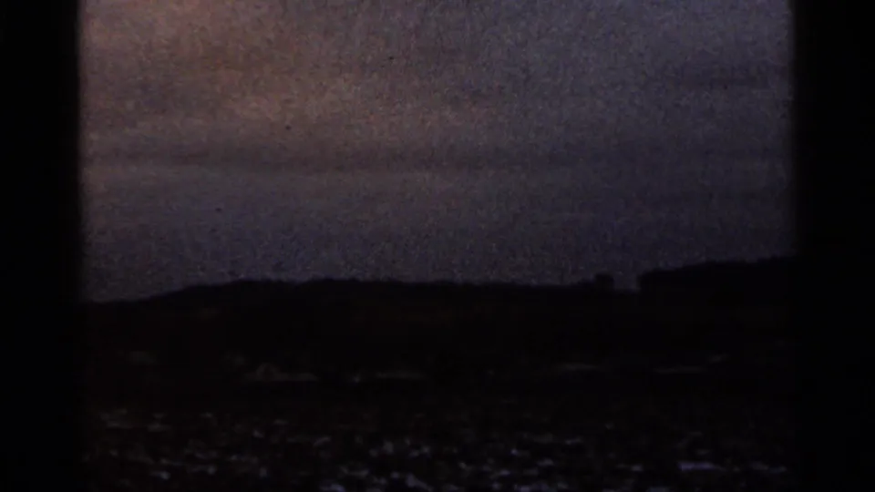 Dark 8mm frame of a low Georgia landscape at dusk or underexposure, with hills and faint ground detail near the horizon.