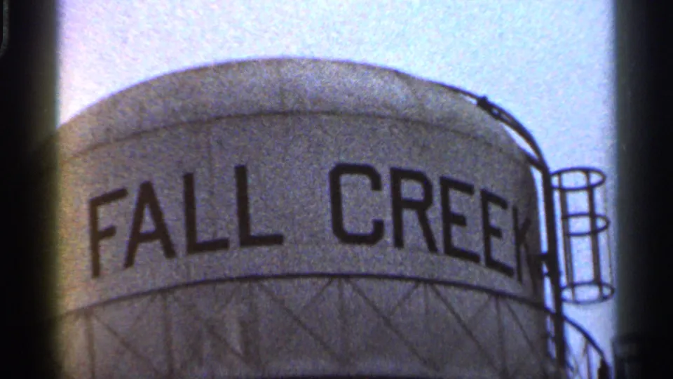 Close 1966 Georgia 8mm view of a large tank marked FALL CREEK, with a side ladder and soft pale sky behind it.