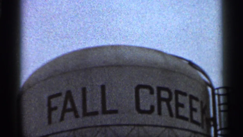 1966 Georgia 8mm frame showing the upper curve of a water tower with partial FALL CREEK lettering and dark film edges.