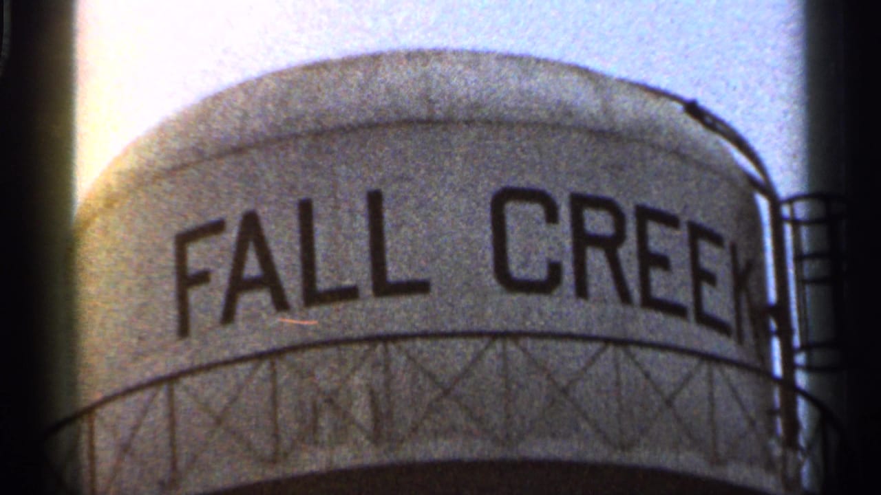 1966 Georgia 8mm frame showing the upper portion of a water tower labeled Fall Creek, with visible film grain and dark gate edges.