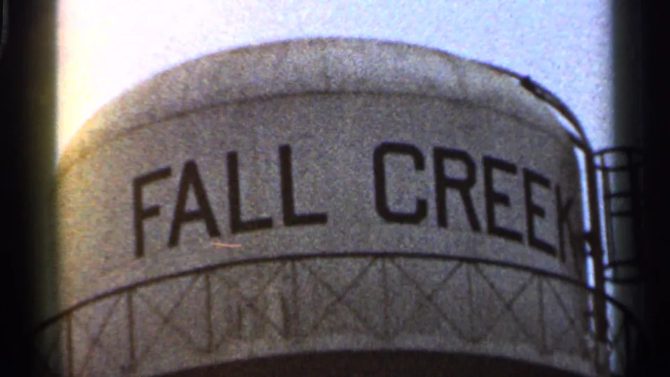 1966 Georgia 8mm frame showing the upper portion of a water tower labeled Fall Creek, with visible film grain and dark gate edges.