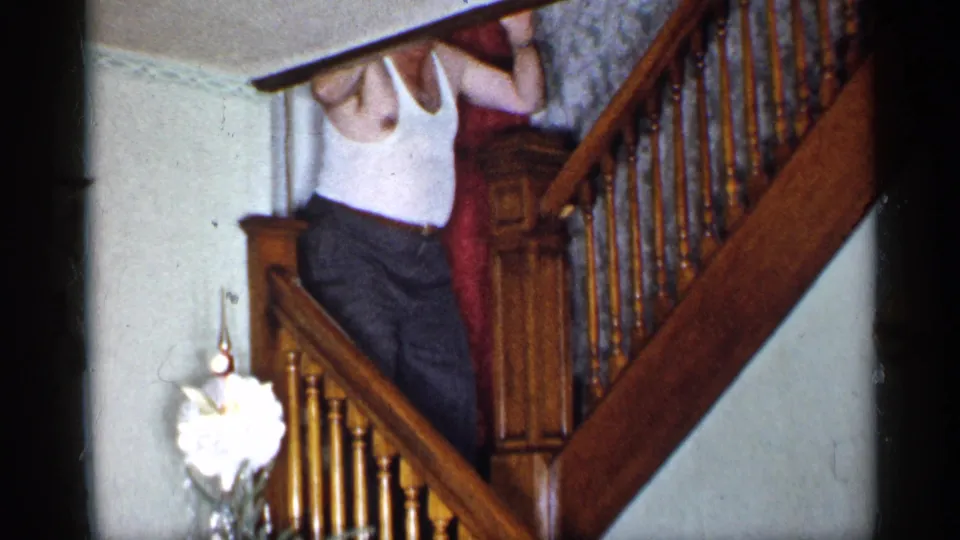 Near the end of the 1955 New York clip, the man is partly cropped while climbing past the staircase rail above the tree.