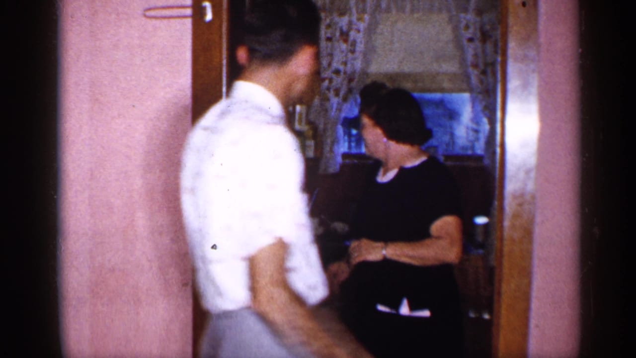 Man and woman near a doorway in a pink-walled home interior.
