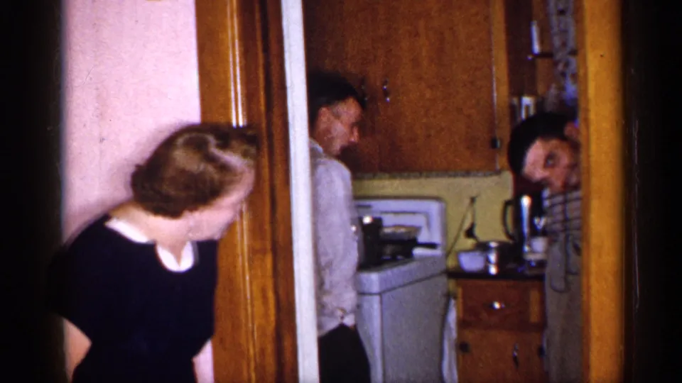 At the end of the 1955 New York home-movie clip, the woman looks into the kitchen while a man and another adult appear near the doorway.