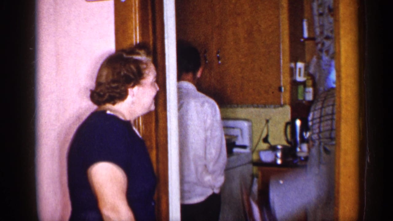 1955 New York interior frame with a woman at a doorway and a man turned away inside the kitchen.