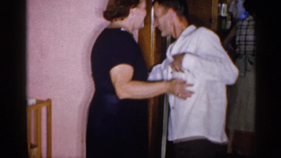 1955 New York home-movie frame showing a woman in a dark dress and a man in a white shirt dancing near a doorway.