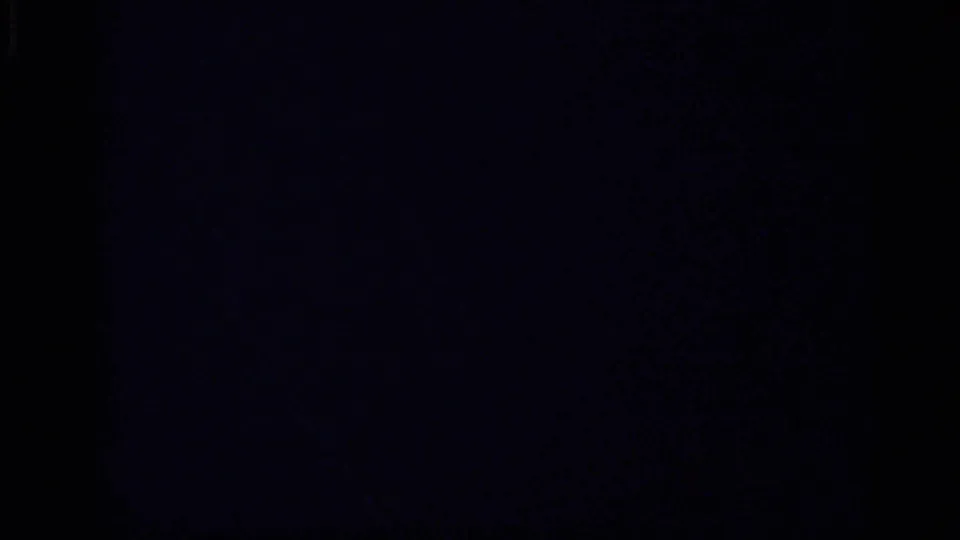 A largely underexposed 8mm frame shows dark film area with only faint edge detail from the interior sequence.