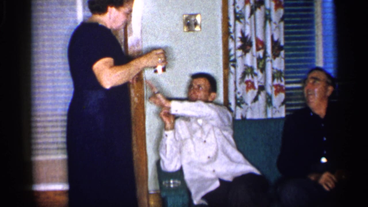 Seated man reaches toward a standing woman while another man watches.