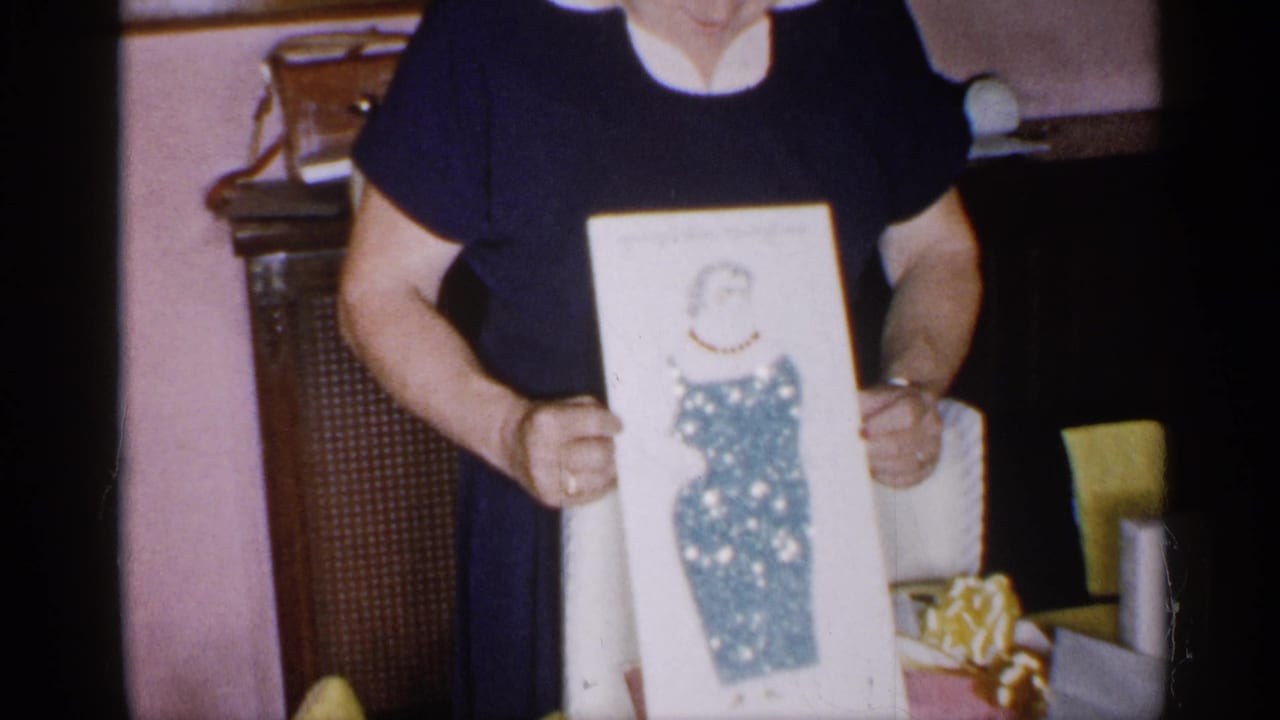 Woman holds the framed illustration closer to the camera indoors.