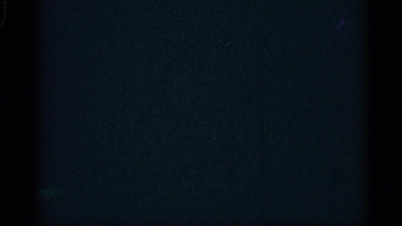 Dark 8mm frame with faint blue exposure and film edge shadows.