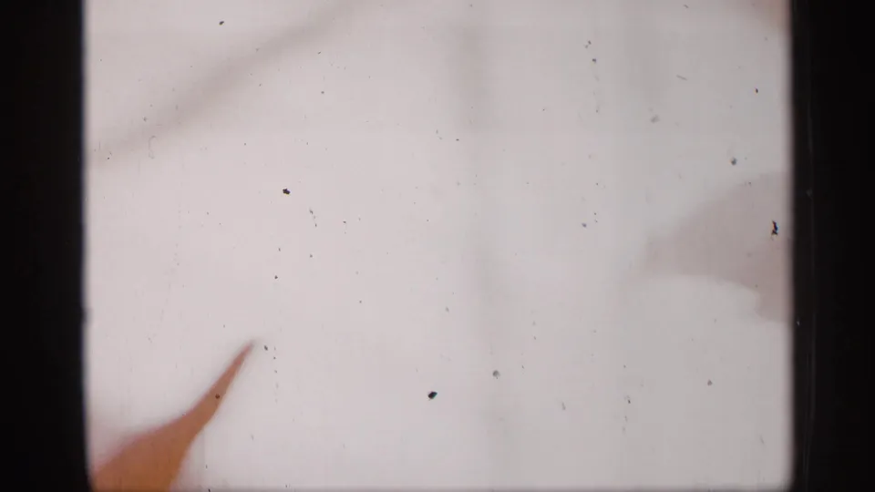 A partial figure or prop crosses the lower frame against a pale backdrop in the 8mm show footage.