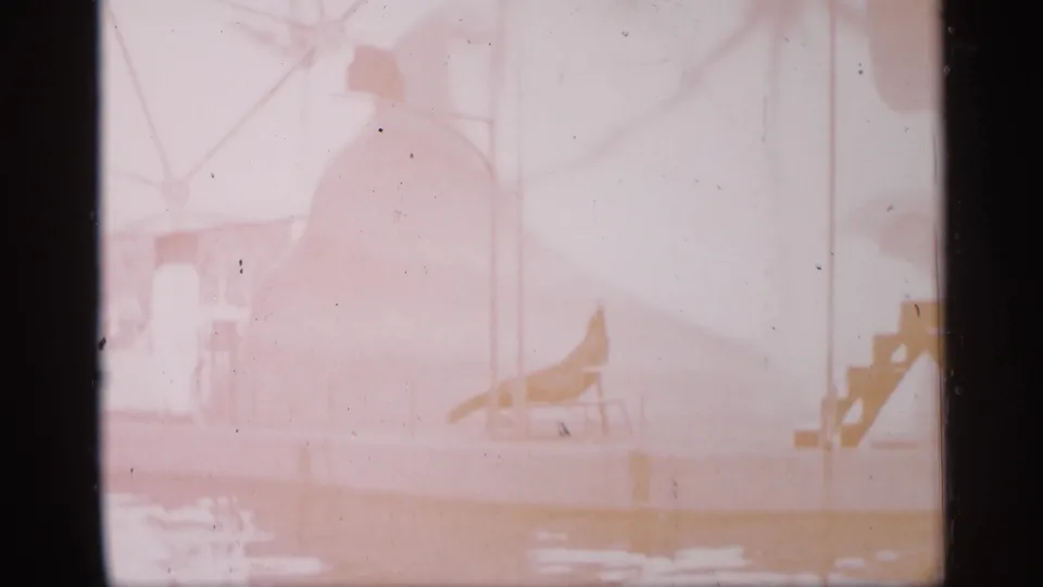 Overexposed 1958 Alabama 8mm frame showing the circus performance area with red-and-white stairs, platform, and faint animal-act shapes.