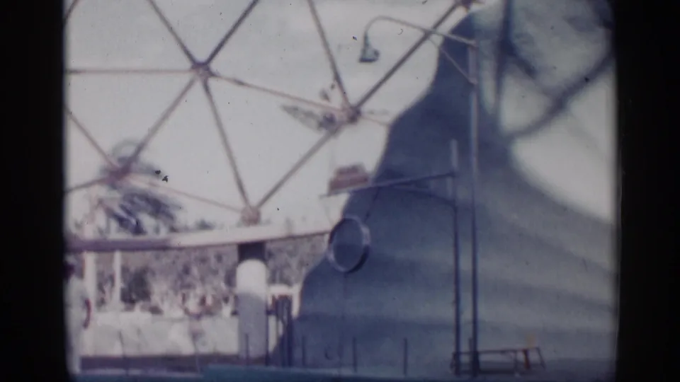 Soft 8mm frame of the marine-show area, with the trainer partly visible beside railings and dome supports.