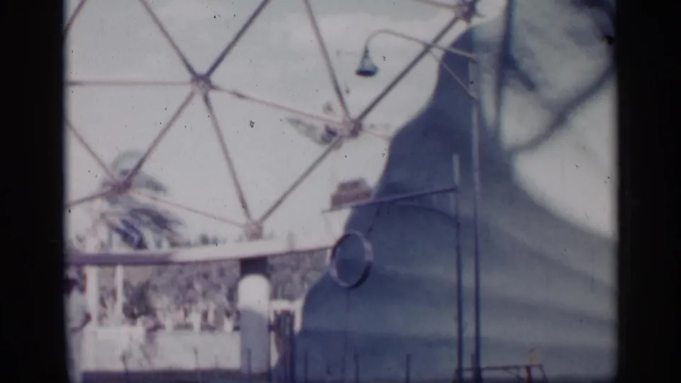 The final frame shows the trainer near the show pool, with dome supports and railings in faded 8mm color.