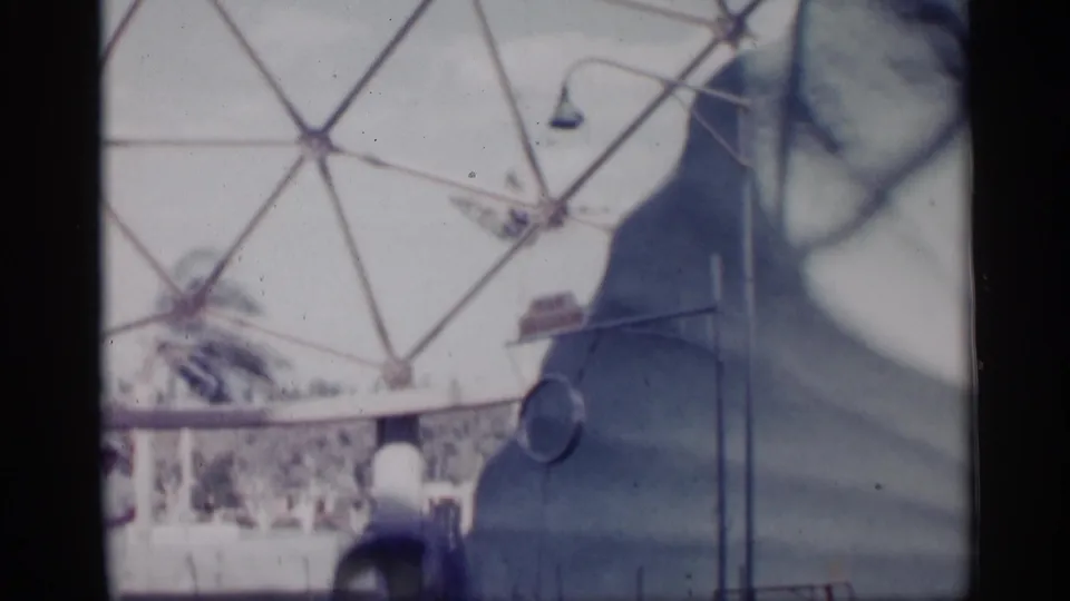 1958 Alabama frame of the marine show setting, with a trainer near the pool and a curved wall beneath a dome-like background structure.