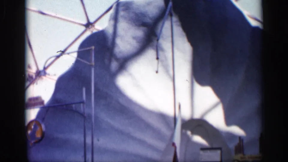 1958 Alabama 8mm frame showing the marine show backdrop, pool edge, and a dolphin shape near the right side of the performance area.