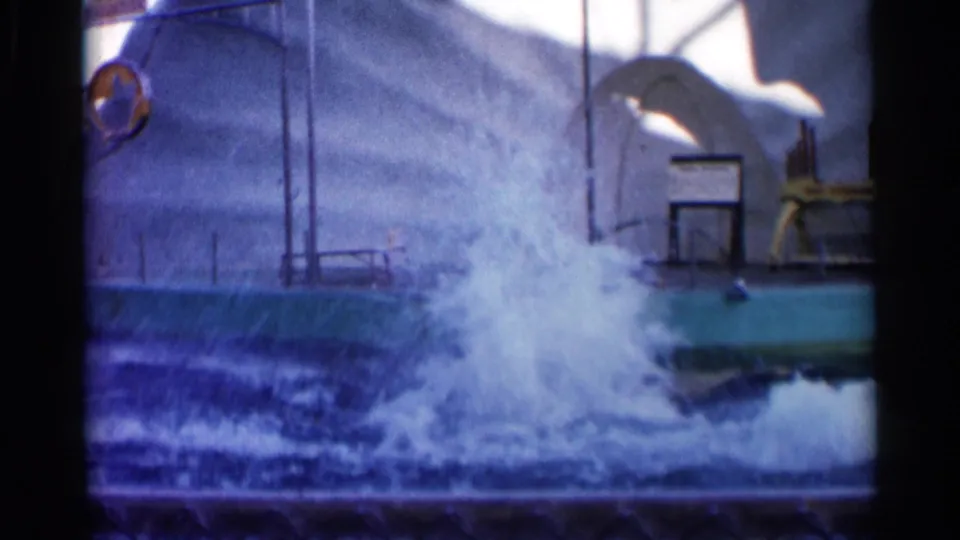 1958 Alabama home-movie frame with a large splash in the marine park pool, suggesting a dolphin jump or dive during the performance.