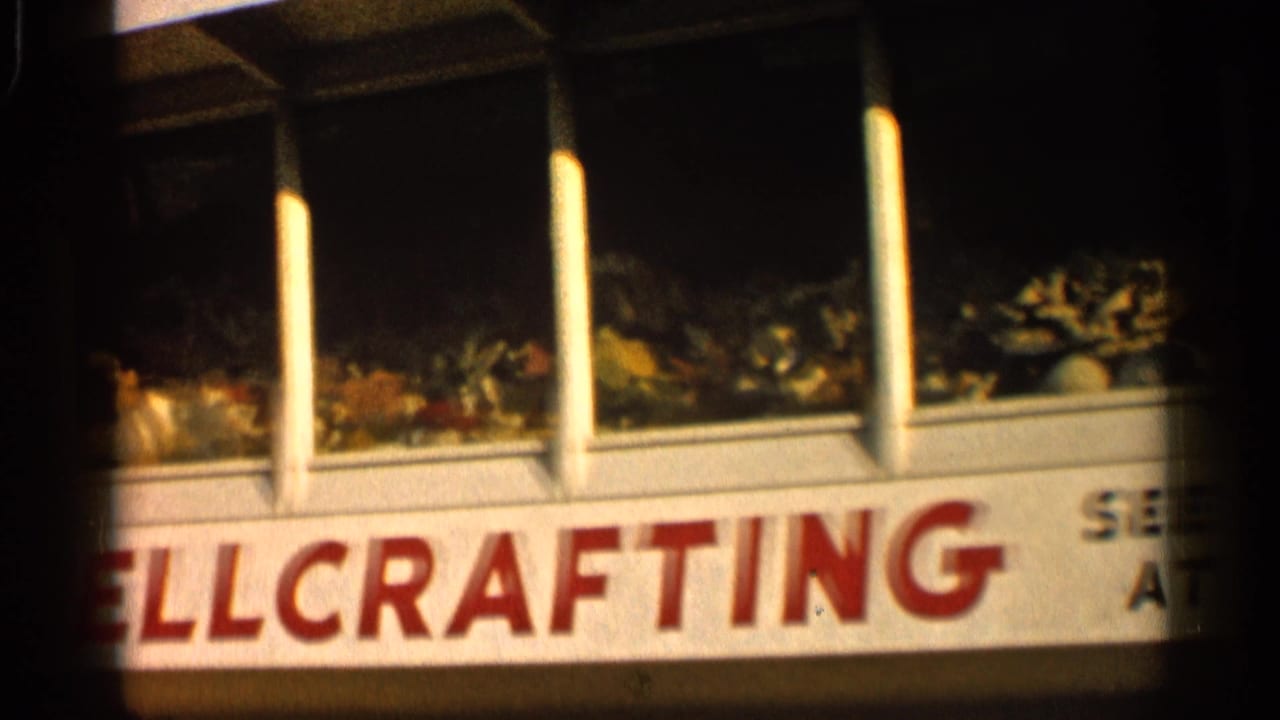 1958 Alabama 8mm frame showing a red and white SHELLCRAFTING storefront sign with shell displays behind windows.