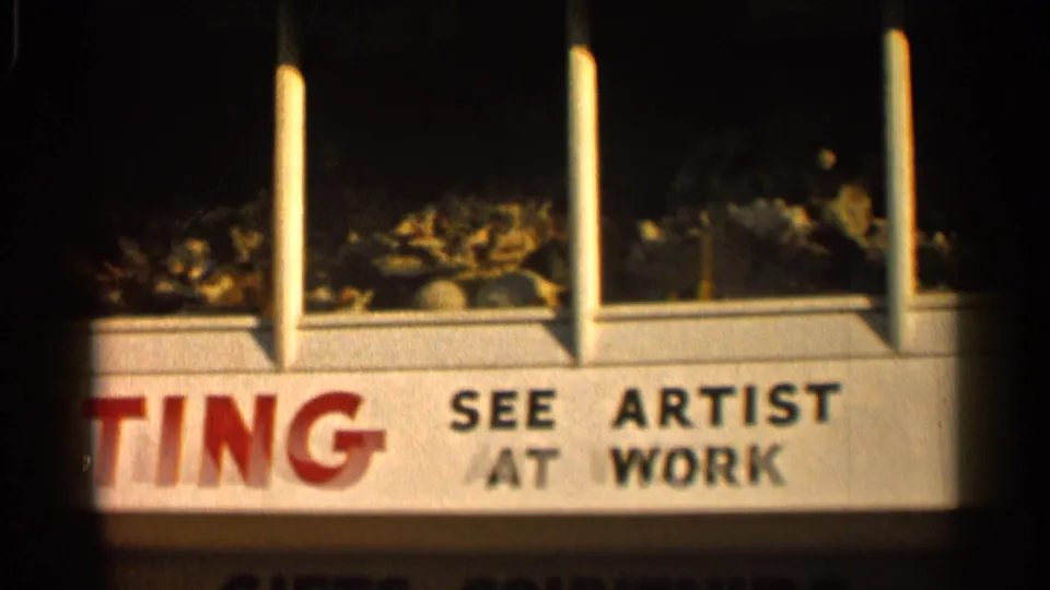 1958 Alabama frame with SEE ARTIST AT WORK text on a white storefront sign and shell displays visible above.