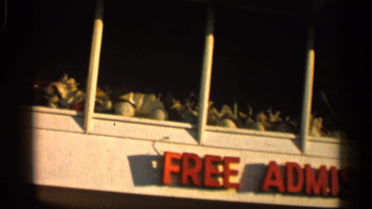 1958 Alabama 8mm frame showing upper storefront windows and part of a red free admission sign at a roadside attraction.