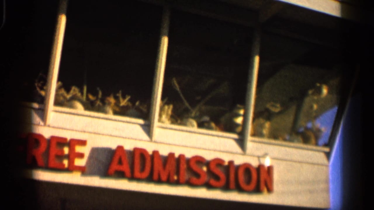 1958 Alabama 8mm frame with red free admission lettering below large windows displaying plants or attraction items.