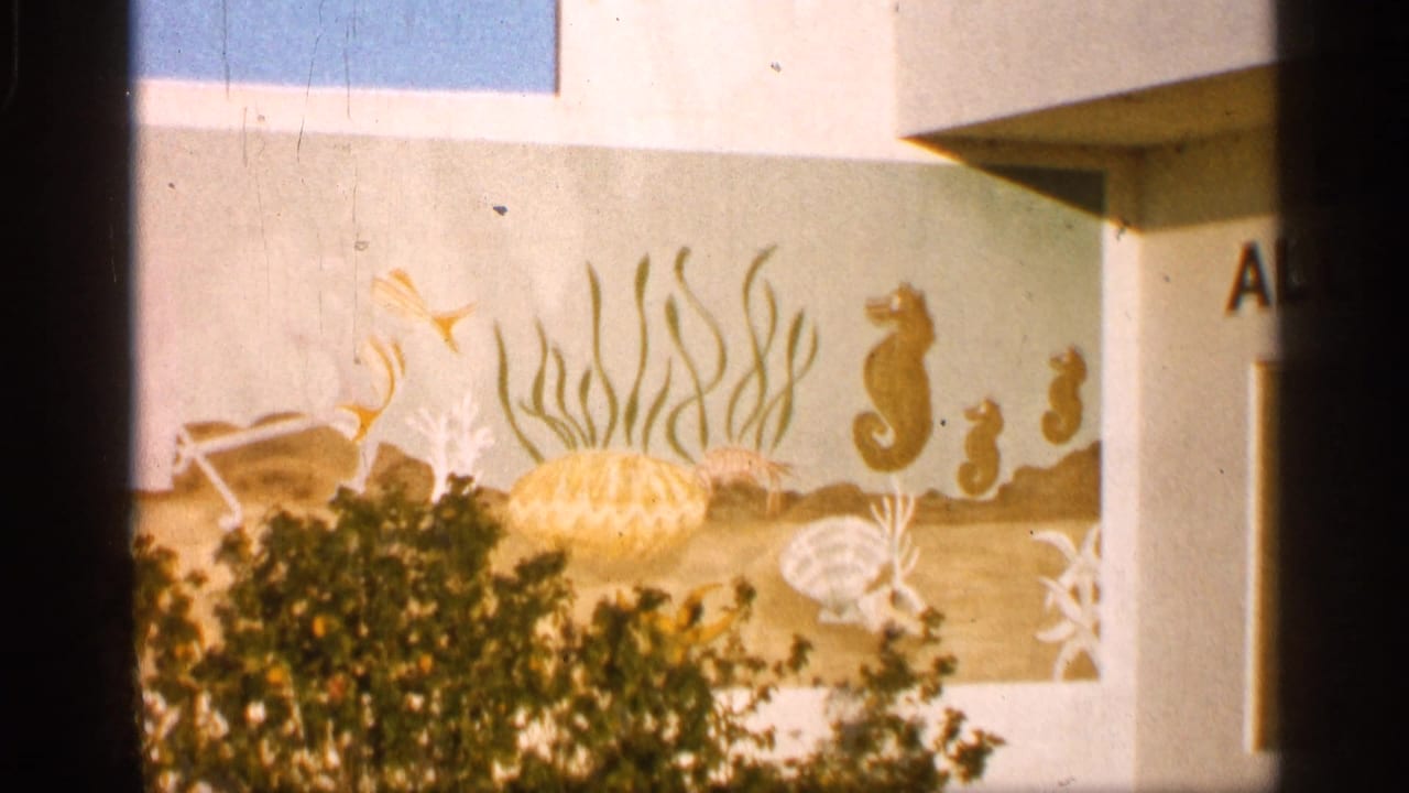 1958 Alabama tourist-shop exterior with a painted marine mural showing seahorses, fish, shells, seaweed, and shrubs in front.