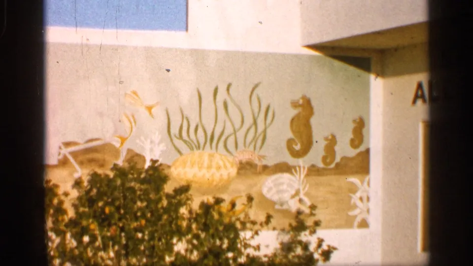 1958 Alabama tourist-shop exterior with a painted marine mural showing seahorses, fish, shells, seaweed, and shrubs in front.