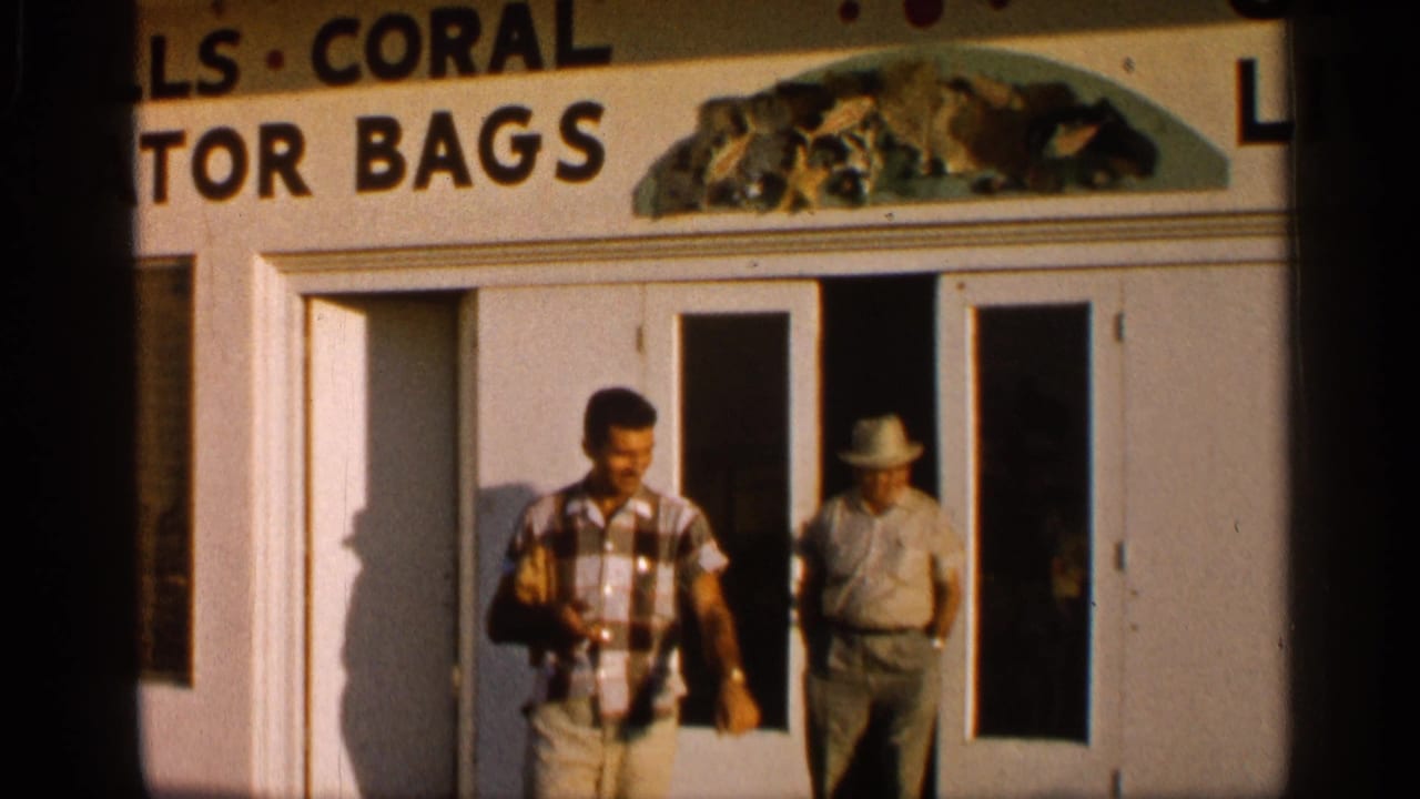 A man in a plaid shirt walks away from a storefront while another man stands near the door.