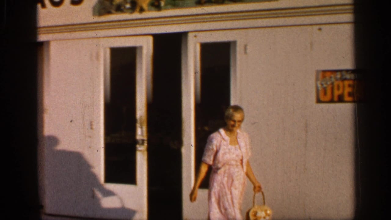 Woman in a pink dress walks from a white building while carrying a basket.