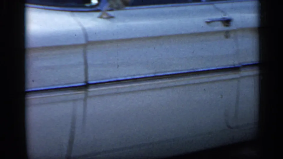 A side view in the 1958 Florida footage shows the white classic car's doors, handles, chrome trim, and lower body panel from close range.