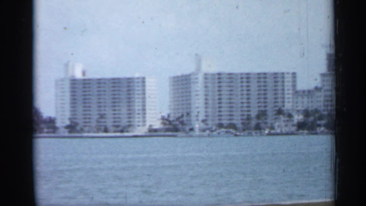 Tall waterfront buildings stand across a broad stretch of water.