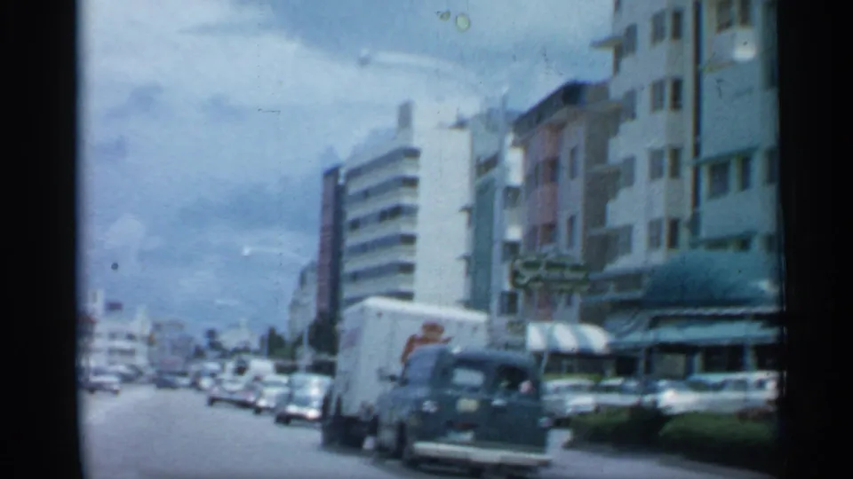 1958 Florida street scene showing classic cars, a white delivery truck, storefront awnings and rows of mid-century commercial buildings.