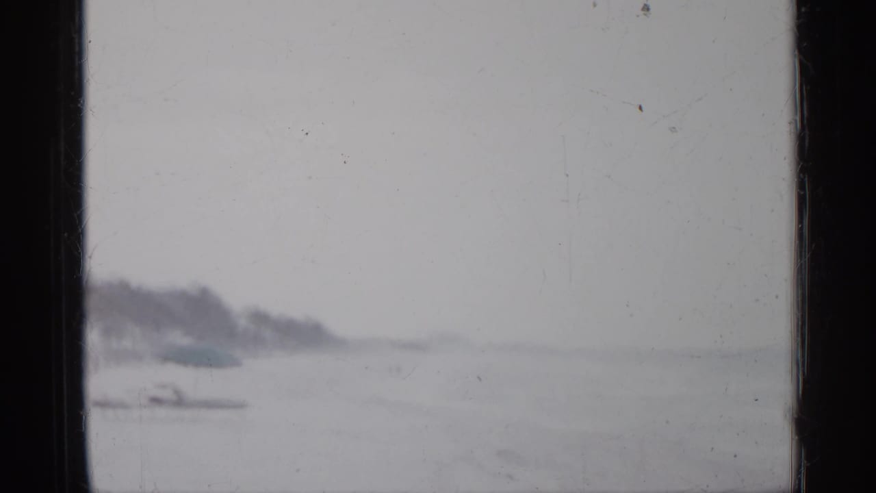 Hazy shoreline with rough water and a dark film gate edge.