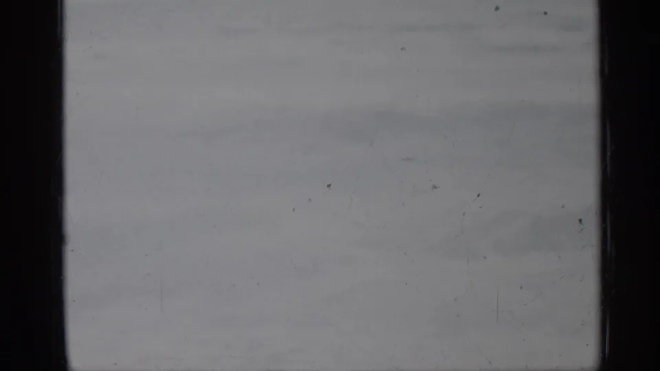 Overexposed 1958 Florida 8mm frame with dark side border, pale gray tones, dust specks, scratches, and indistinct background patches.