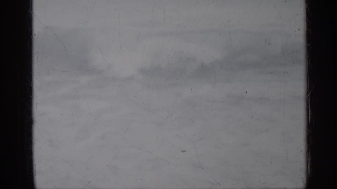 Distant ocean horizon with soft waves under an overcast sky.