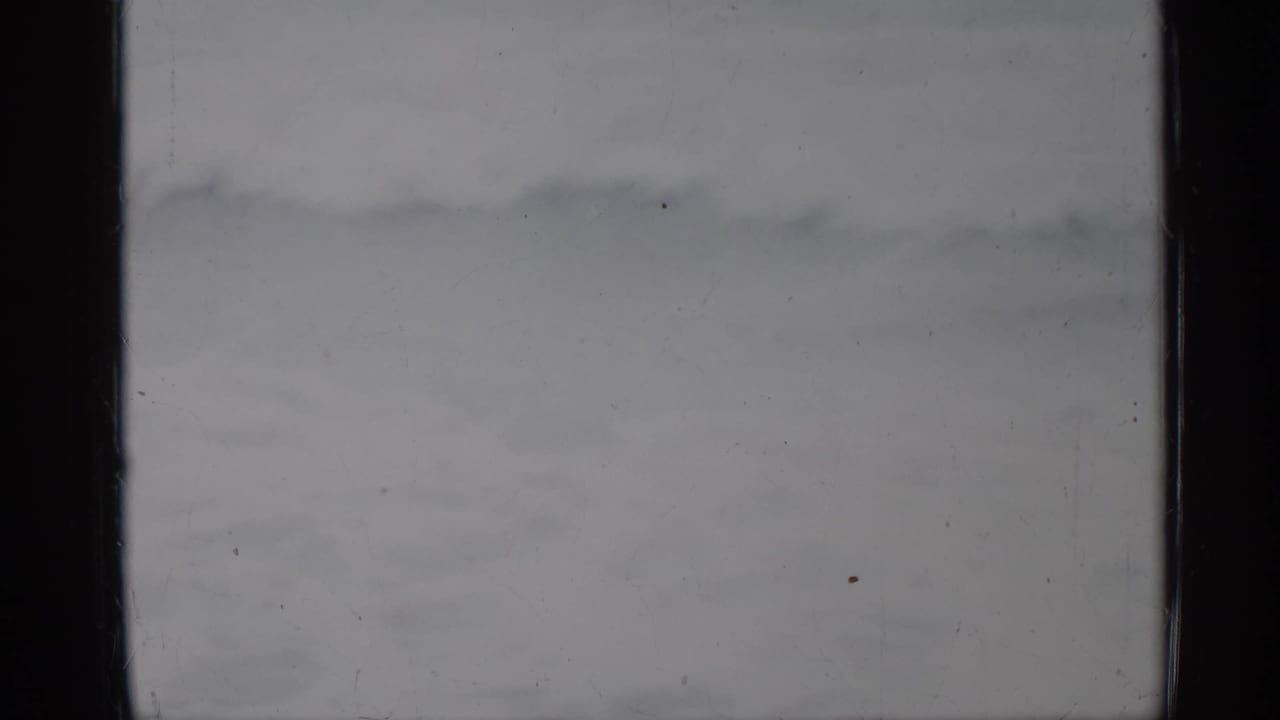 Faint ocean waves move across a pale, grainy seascape.
