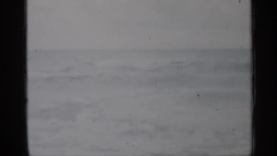1958 Florida 8mm frame of distant shoreline surf, small waves, and subdued overcast coastal light.