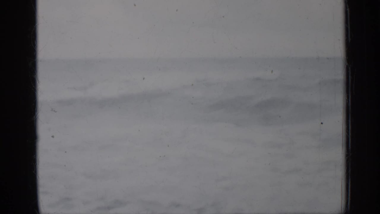 Gray ocean horizon with choppy waves seen through dark 8mm frame edges.