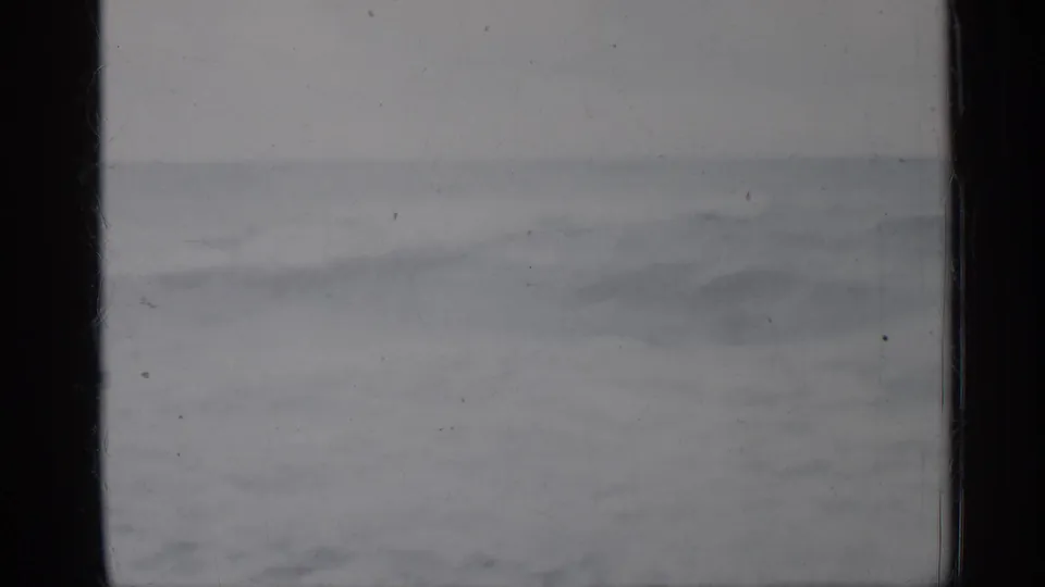 1958 Florida home-movie frame showing a gray ocean horizon, rough water, and visible film grain with dark frame borders.