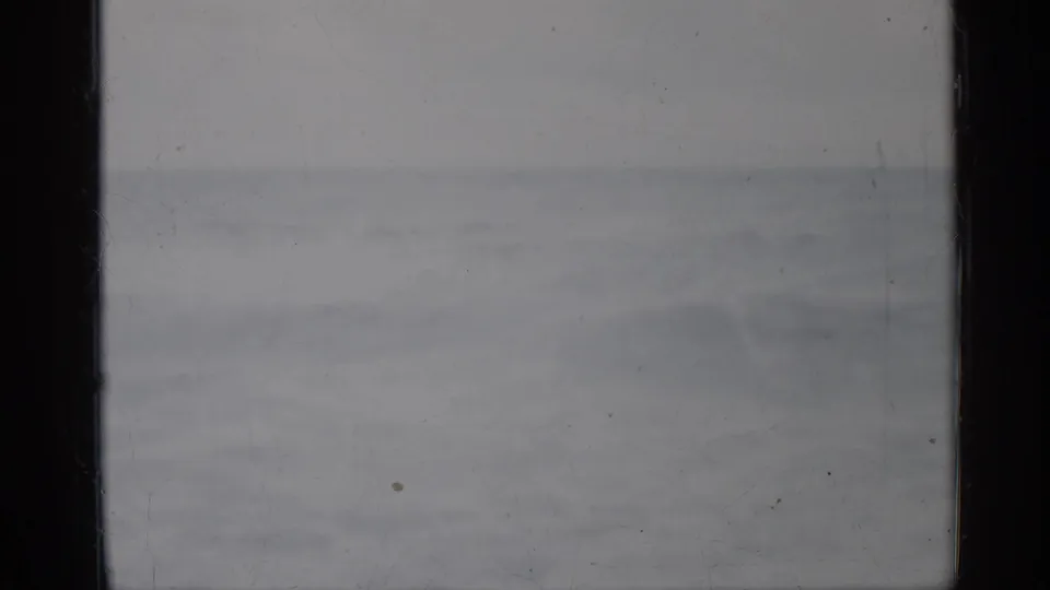 1958 Florida ocean shot with soft gray surf, a distant horizon, dark film gate edges, dust, and uneven exposure.