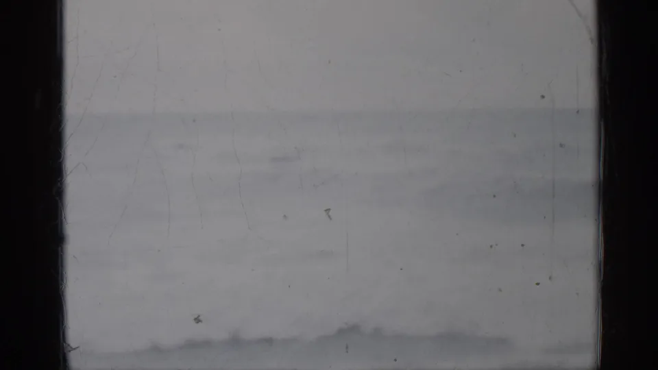1958 Florida 8mm home-movie frame showing a muted seascape, low surf, pale horizon, and visible film wear at the gate edges.
