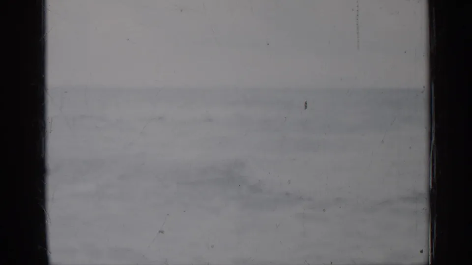 1958 Florida 8mm frame with gentle ocean swell, pale sky, soft focus, and vertical gate borders from the physical film scan.