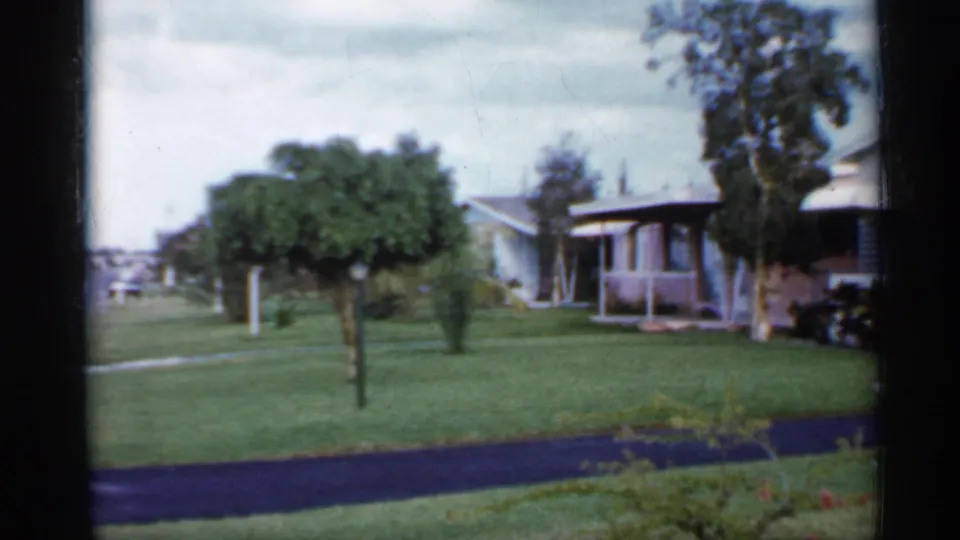 1958 Florida frame showing front yards, small trees, a driveway, and single-story residential houses viewed from the street.