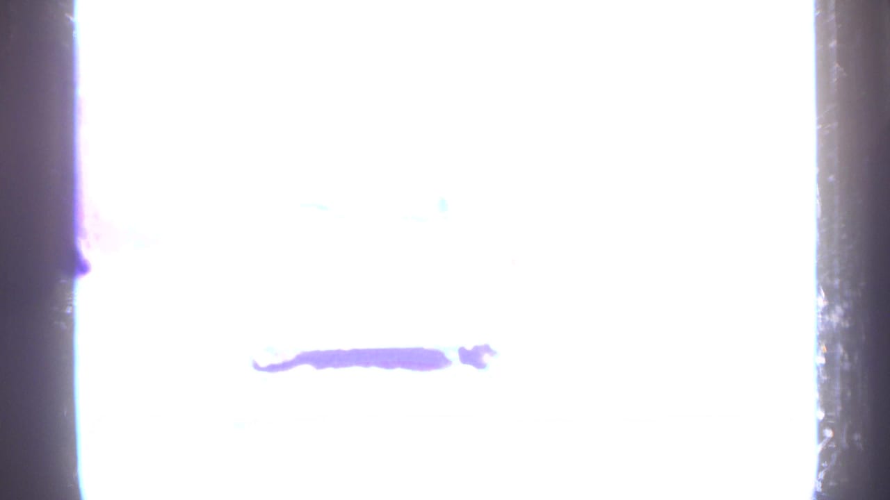 Overexposed purple-white light flare with dark film edges.