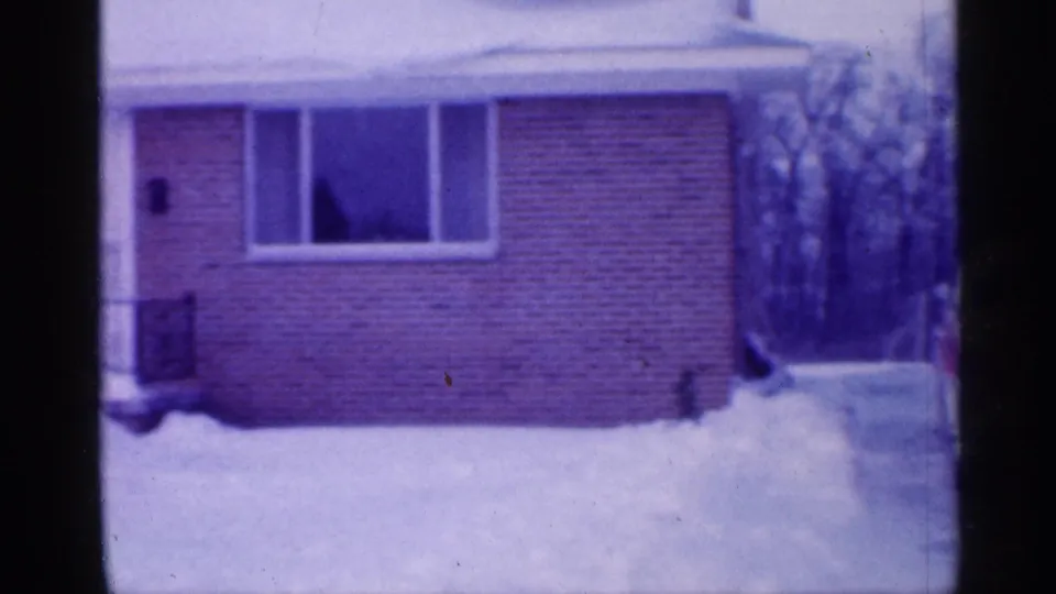Snowy New Jersey suburban house exterior with brick facade, picture window, driveway, and bare trees in the background.